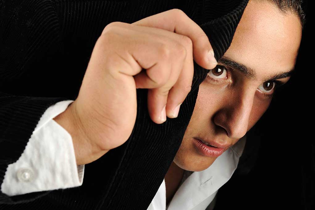 Portrait of a serious young man making headscarf with his jacket